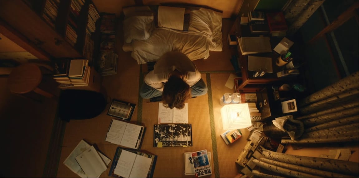 An overhead view of a man reading books in a dimly lit room