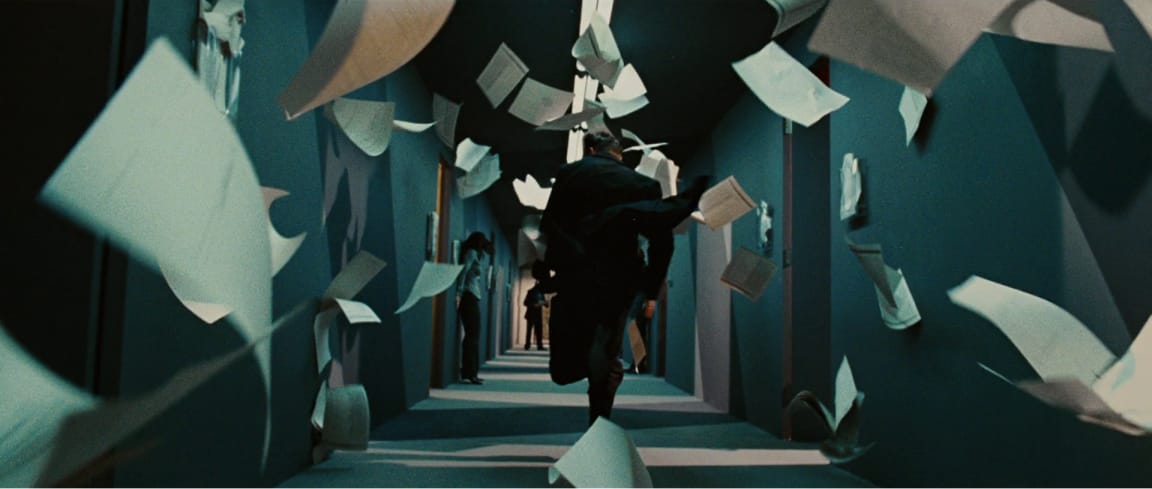 Man running down a hallway with papers flying about