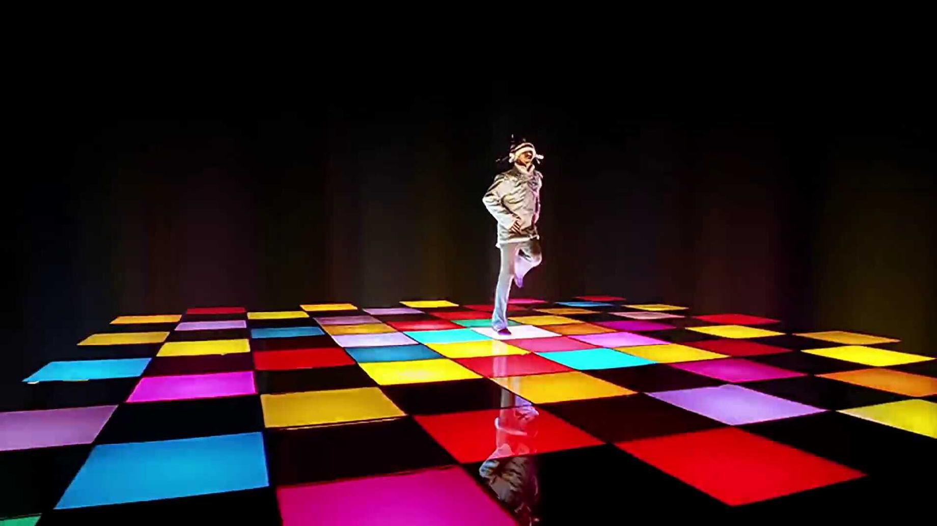 Man with a robot helmet on a colourful nightclub stage