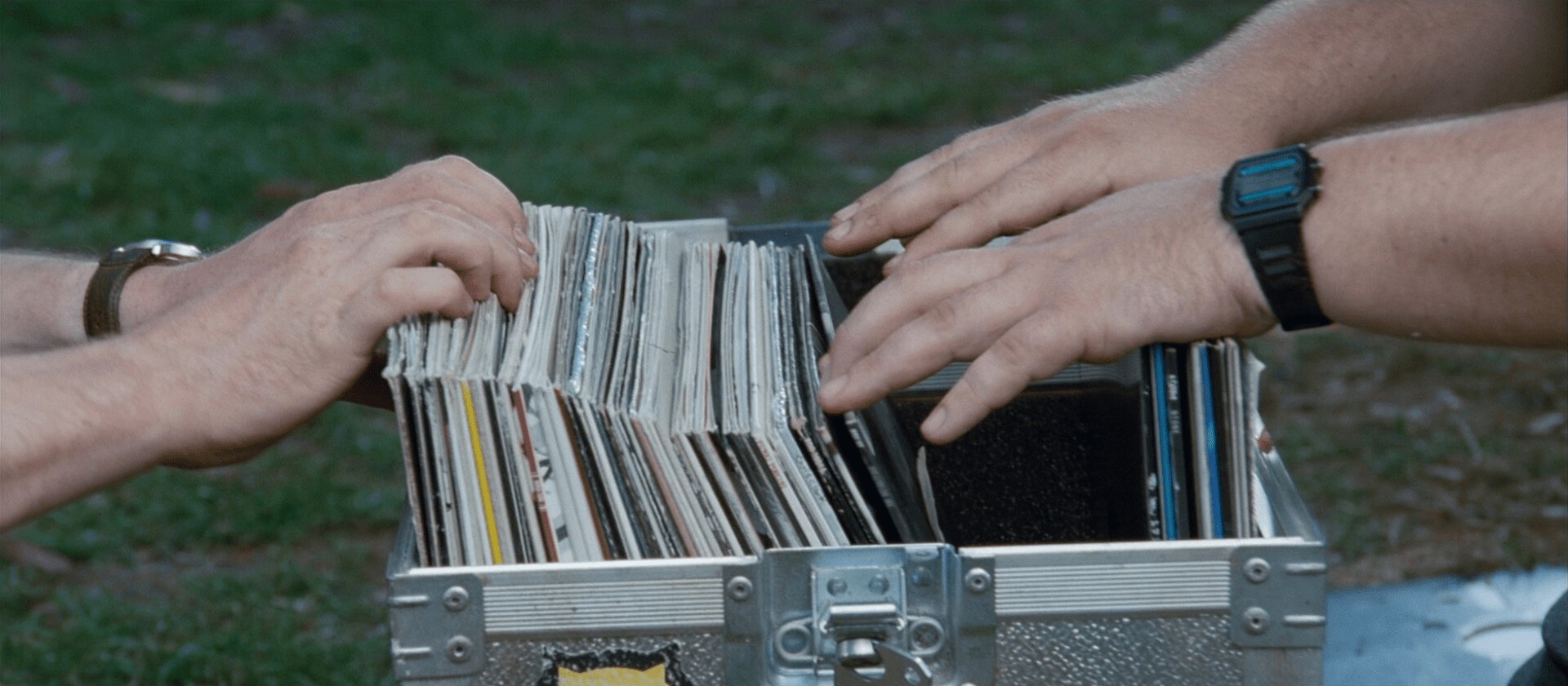 Picture of 4 hands going through a box of vinyls to find a song